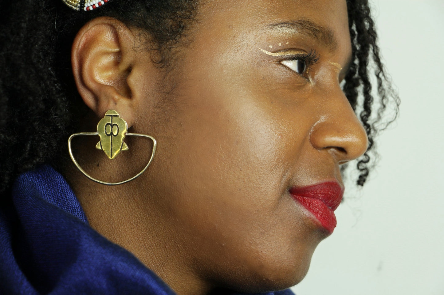 Les boucles d'oreilles Ifé, portée par une femme portant un drapé bleu.