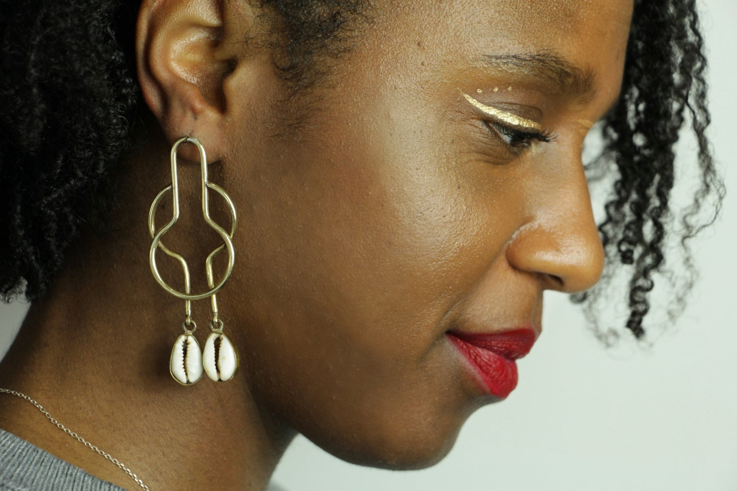 Boucles d'oreilles Kyassa portée par une femme au maquillage afro ethnique.