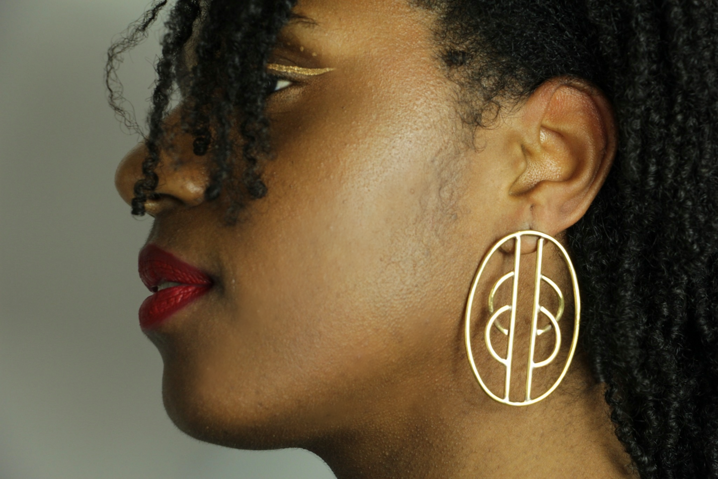 Boucles d'oreilles Kyassa portée par une femme au maquillage afro ethnique.